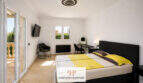 Helles Schlafzimmer der Villa Sa Torre mit Doppelbett, Balkonzugang und modernem Deckenleuchter in Llucmajor