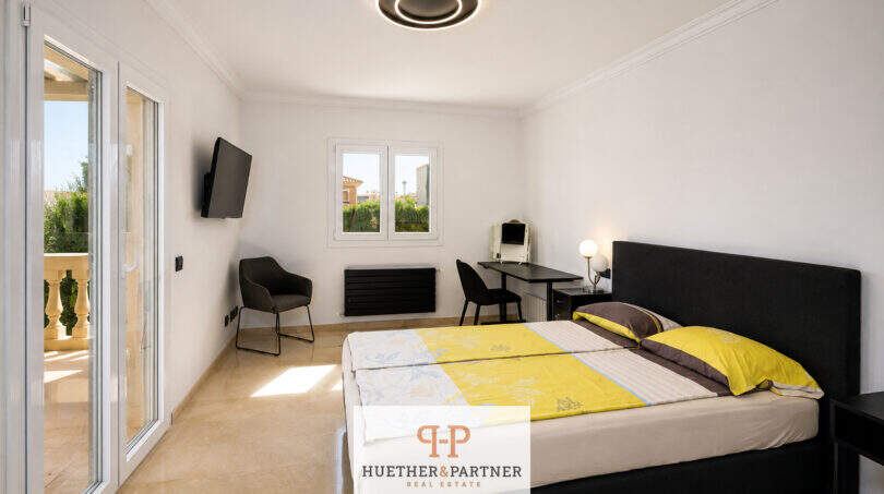 Helles Schlafzimmer der Villa Sa Torre mit Doppelbett, Balkonzugang und modernem Deckenleuchter in Llucmajor