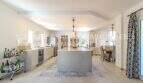 Moderne offene Küche mit Kochinsel, Hängelampen und Barwagen in mediterraner Villa, Sa Coma