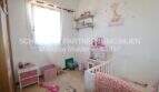 Habitación infantil con cuna blanca, juguetes, decoración rosa y pegatina de jirafa en la pared en apartamento cerca del mar, Porto Cristo