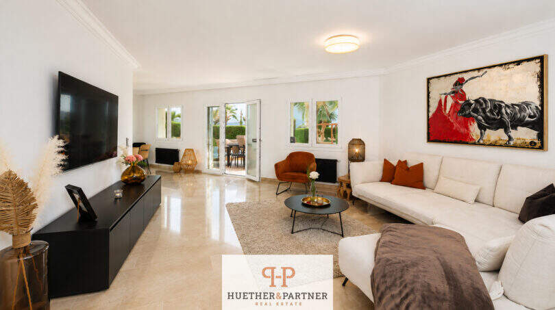 Helles Wohnzimmer der Villa Sa Torre mit Marmorboden, weißem Sofa, Stierbild und Terrasse mit Meerblick
