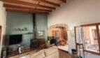 Wohnzimmer der Finca in Llucmajor mit Holzbalkendecke, Kaminofen, Sofa und Blick ins Esszimmer.