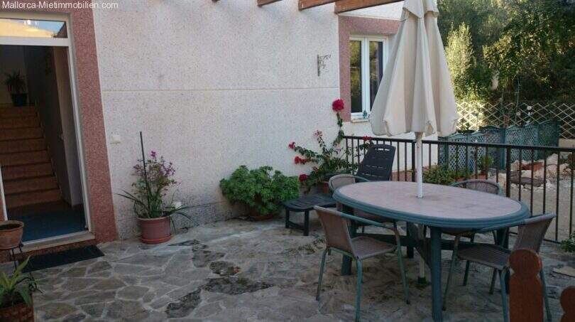 Sunny terrace with natural stone floor, garden furniture and umbrella at the chalet in Cala Murada