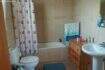 Bathroom of the chalet in Cala Murada with bathtub, toilet, sink and wooden dresser, bright tiled walls