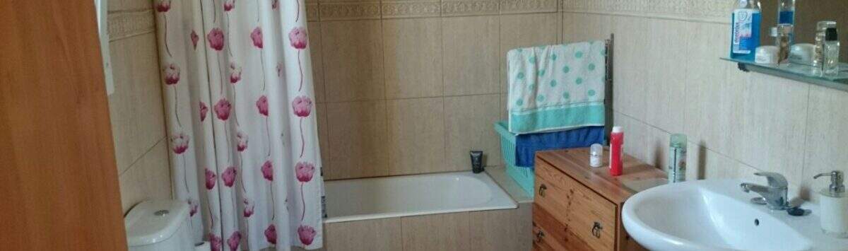 Bathroom of the chalet in Cala Murada with bathtub, toilet, sink and wooden dresser, bright tiled walls