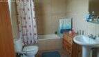 Bathroom of the chalet in Cala Murada with bathtub, toilet, sink and wooden dresser, bright tiled walls