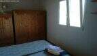 Bedroom of the Cala Murada chalet with wooden wardrobe, double bed and window with forest view.
