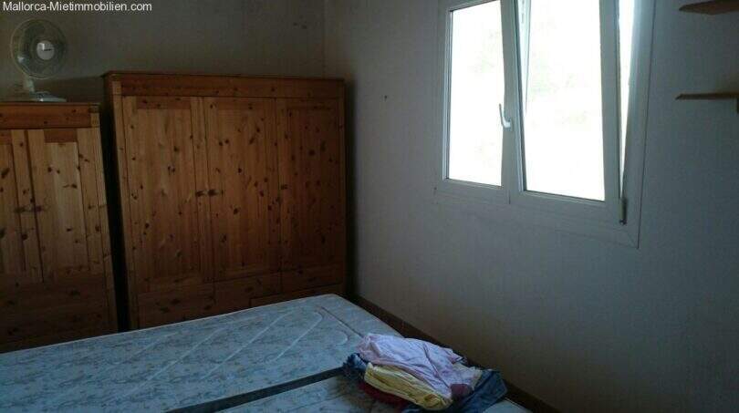 Bedroom of the Cala Murada chalet with wooden wardrobe, double bed and window with forest view.