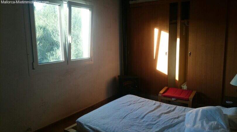Bedroom of the Cala Murada chalet with double bed, built-in wardrobe and window with forest view.