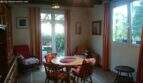Bright dining room in the Cala Murada chalet with wooden table, red curtains and terrace door to the garden with forest view.