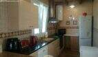 Kitchen of the chalet in Cala Murada with dark countertop, built-in appliances, tiles and forest view through the window.