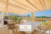 Sonnige Terrasse mit Markise, Essbereich, Lounge und Grillplatz, Blick auf Garten und Nachbarschaft in Porto Cristo Novo.