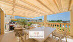 Sonnige Terrasse mit Markise, Essbereich, Lounge und Grillplatz, Blick auf Garten und Nachbarschaft in Porto Cristo Novo.