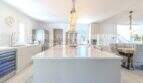 Moderne Küche mit großer Marmorinsel, Weinkühlschrank und Pendelleuchten in mediterraner Villa, Sa Coma