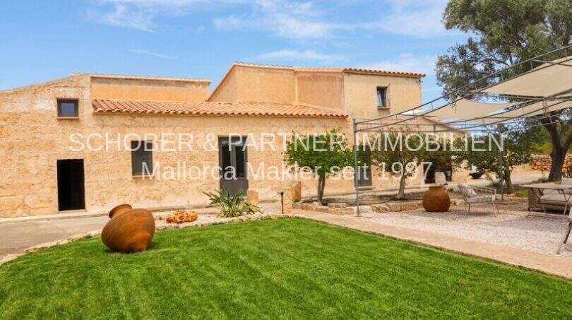 Saniertes Mallorca-Landhaus mit gepflegtem Rasen, Sandsteinfassade, Terrakotta-Amphoren und überdachter Terrasse