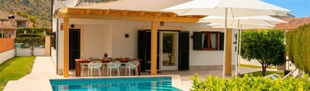 Bungalow Alcúdia: Terrasse mit Pergola, Esstisch und türkisblauem Salzwasserpool, Bergpanorama im Hintergrund