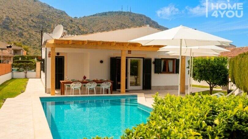 Bungalow Alcúdia: Terrasse mit Pergola, Esstisch und türkisblauem Salzwasserpool, Bergpanorama im Hintergrund