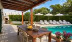 Covered terrace with dining table, salt water pool and sun loungers in the garden of the bungalow in Alcúdia.