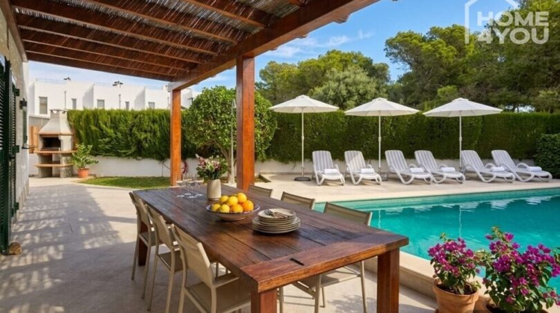 Covered terrace with dining table, salt water pool and sun loungers in the garden of the bungalow in Alcúdia.