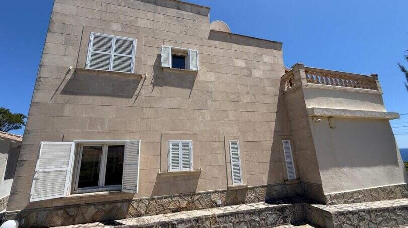 Außenansicht der mediterranen Villa in Cala Murada mit Natursteinverkleidung und weißen Fensterläden.