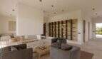 Modernes Wohnzimmer mit Kamin, grauen Sesseln, Holzcouchtisch und beleuchtetem Wandregal in Designvilla Cala Murada