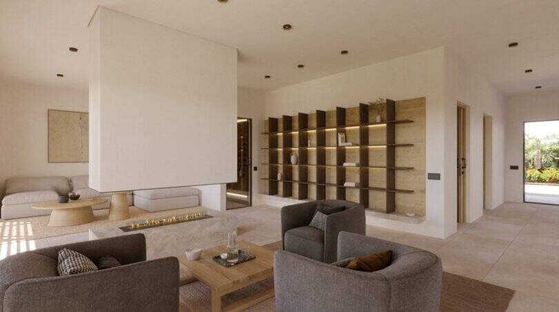 Modernes Wohnzimmer mit Kamin, grauen Sesseln, Holzcouchtisch und beleuchtetem Wandregal in Designvilla Cala Murada