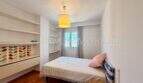 Helles Schlafzimmer der Dachgeschosswohnung Blanquerna Palma mit Einzelbett, Holzboden und weißen Wandregalen.