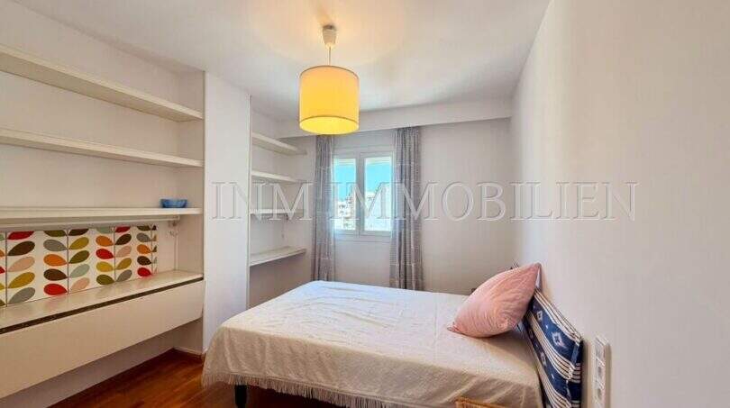 Helles Schlafzimmer der Dachgeschosswohnung Blanquerna Palma mit Einzelbett, Holzboden und weißen Wandregalen.