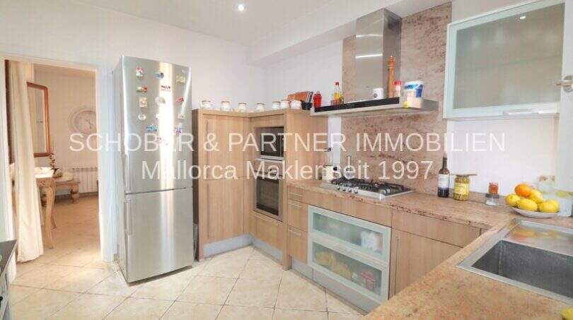 Modern fitted kitchen with wooden fronts, stainless steel refrigerator and granite countertop in Son Servera