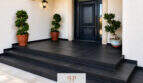 Eleganter Hauseingang der Villa Sa Torre mit schwarzer Designtür, Natursteinstufen und mediterranen Topfpflanzen