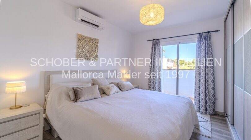 Elegantes Schlafzimmer der mediterranen Villa in Sa Coma mit Doppelbett, Klimaanlage und Balkonzugang.