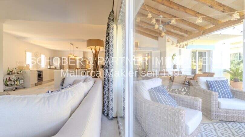 Eleganter Wohnbereich mit weißen Sofas, Holzbalkendecke und Übergang zur mediterranen Terrasse in Villa Sa Coma.