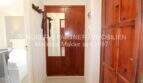Entrada del apartamento en Cala Ratjada con armario de madera, espejo y puerta de entrada rústica