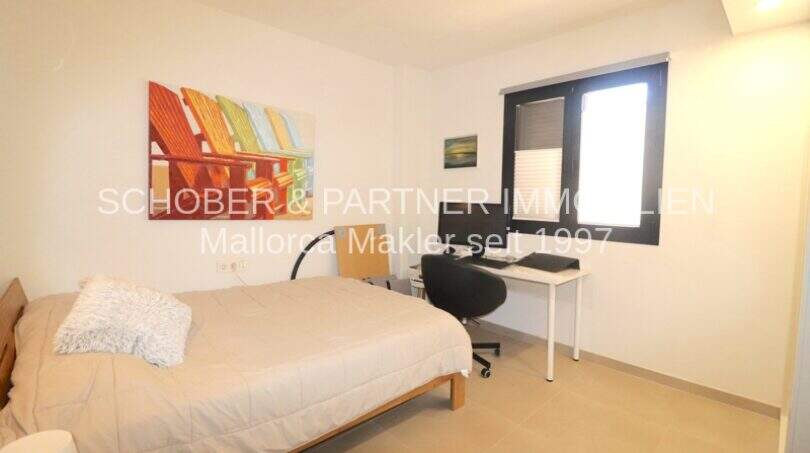 Helles Schlafzimmer mit Doppelbett, Schreibtisch und buntem Wandbild in hochwertiger Gartenwohnung in Sa Coma