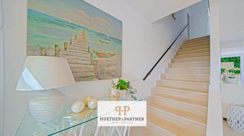 Heller Eingangsbereich mit Holztreppe, Kunstgemälde und eleganter Dekoration im Reiheneckhaus Porto Cristo Novo.