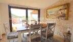 Dining room with rustic wooden table, natural stone wall and large window with panoramic view in Son Servera
