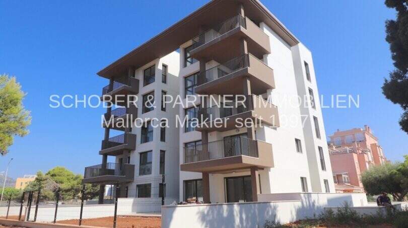 Moderno complejo de apartamentos de nueva construcción en Cala Millor con balcones, fachada blanca e instalaciones exteriores bien cuidadas.