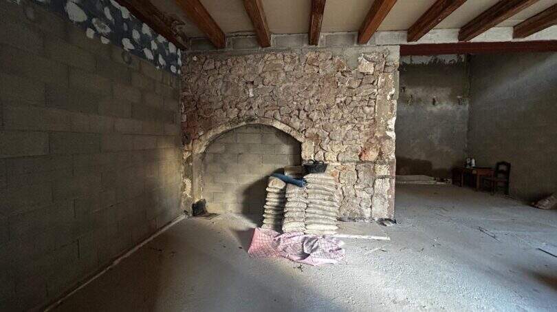 Unrenovierter Raum mit historischem Steinbogen, Holzbalkendecke und Baumaterialien im Stadthaus Sant Llorenç