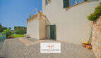Außenbereich Reiheneckhaus Porto Cristo Novo: Kieselfläche, grüne Fensterläden, Terrasse mit Balustrade und üppiger Gartenbegrünung.
