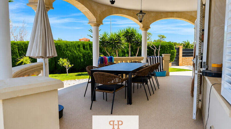 Überdachte Terrasse mit Bogensäulen, Esstisch und Gartenblick der Villa in Sa Torre, Llucmajor