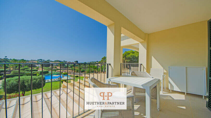 Sonnige Terrasse des Reiheneckhauses in Porto Cristo Novo mit Gartenmöbeln und Blick auf Pool und Grünanlage.
