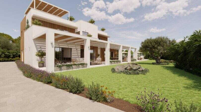 Moderne Designvilla in Cala Murada mit weißer Fassade, Pergola, gepflegtem Garten und mediterraner Bepflanzung.