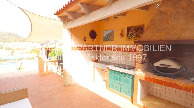 Covered outdoor kitchen with grill and tiles, terrace with pool and sea view in Son Servera