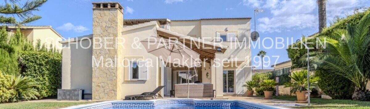 Mediterrane Villa in Sa Coma mit großem Swimmingpool, Steinverkleidung und Palmen im gepflegten Garten.