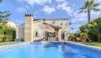 Mediterrane Villa in Sa Coma mit großem Swimmingpool, Steinverkleidung und Palmen im gepflegten Garten.