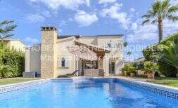 Mediterrane Villa in Sa Coma mit großem Swimmingpool, Steinverkleidung und Palmen im gepflegten Garten.