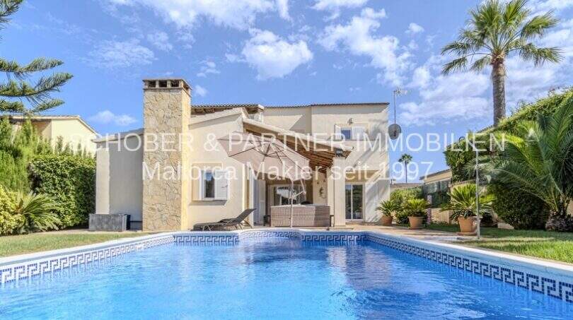 Mediterrane Villa in Sa Coma mit großem Swimmingpool, Steinverkleidung und Palmen im gepflegten Garten.