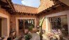 Mediterraner Innenhof der Finca Llucmajor mit Natursteinmauern, Terrakottadach und üppigen Topfpflanzen.