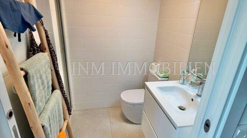 Modernes Badezimmer der Wohnung in Cala d'Or mit Waschbecken, WC und Handtuchleiter.
