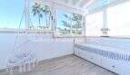 Helles Schlafzimmer mit Hängestuhl, Einzelbett und Palmenblick in mediterraner Villa Sa Coma